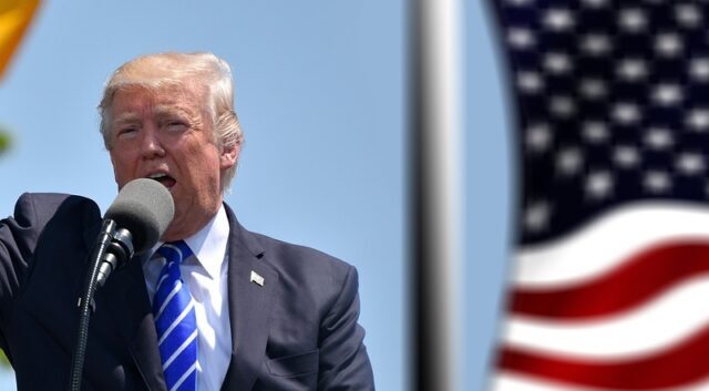 Donald Trump dando un discurso, con una bandera de Estados Unidos al fondo.